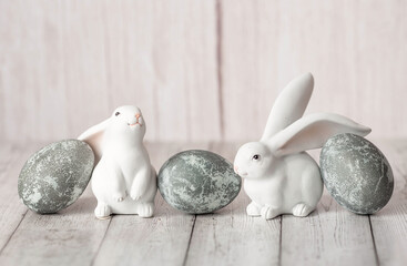 Stylish grey Easter eggs in the colors of marble, concrete, willow branches and Easter chicken on a white wooden background. Coloring eggs for Easter.  The feast of bright Easter.