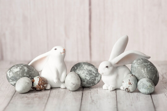 Stylish grey Easter eggs in the colors of marble, concrete, and Easter bunnies on a white wooden background. Coloring eggs for Easter.  The feast of bright Easter.