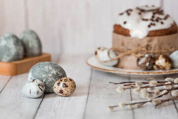 Fototapeta na wymiar Stylish grey Easter eggs in the color of marble, concrete, willow branches and Easter cake on a white wooden background. Coloring eggs with natural dye karkade tea. The feast of bright Easter.