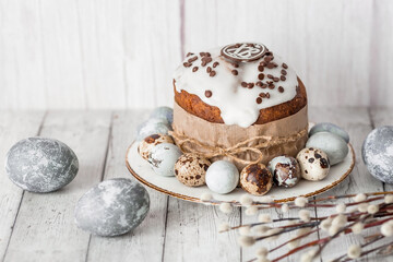 Obraz na płótnie Canvas Stylish grey Easter eggs in the color of marble, concrete, willow branches and Easter cake on a white wooden background. Coloring eggs with natural dye karkade tea. The feast of bright Easter.