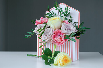 Flower arrangement of multicolored roses in a cardboard gift box