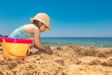 Fototapeta na wymiar Child wearing protective sunhat playing on a beach