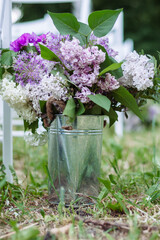 A bouquet of lilac flowers, purple giant onions, carnations, peonies, and other flowers in a small basket as a decorative element in various events like weddings and others - 706327818