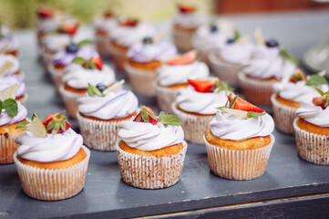 Delicious cupcakes with blueberries, strawberries, and mint on a black table