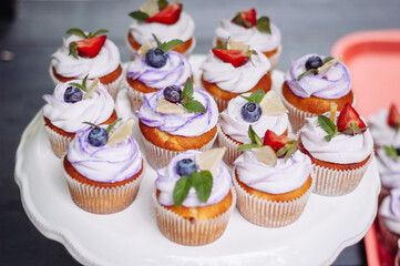 Delicious cupcakes with blueberries, strawberries, and mint on a white plate - 706327863