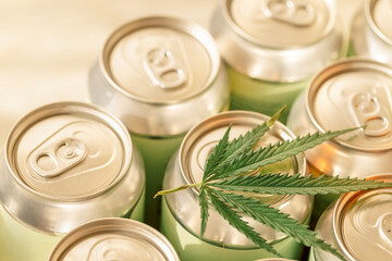 A collection of aluminum cans with a cannabis leaf. Trending concept of CBD-infused beverages with...