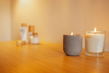 Two lighted candles in a ceramic and glass candlestick on a wooden table. Cosmetic and beauty...