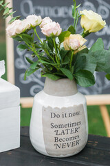 Bouquet of white roses in a ceramic vase. The vase has message 