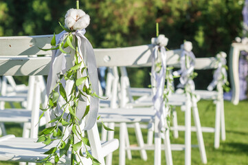 Row of white folding chairs before a wedding ceremony. Seats for guests. - 706329883