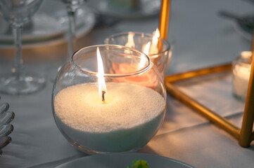 Romantic Ambiance: Wax Candles in Glass Cups Illuminate the Wedding Celebration