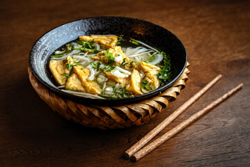 Asian vegetarian noodle soup in a ceramic plate