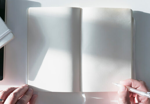 Man Holding Pencil over Blank Page of a Notebook
