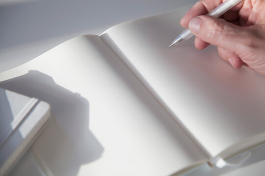 Man Holding Pencil over Blank Page of a Notebook
