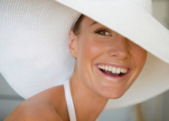 Close up of a young woman wearing a white hat smiling
