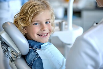A smiling young blond boy in a dental chair. Examination by a dentist - obrazy, fototapety, plakaty