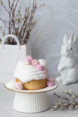 Beautiful stylish still life. Easter cake with meringue, marshmallows, Easter eggs and willow twigs on a light concrete background. happy Easter 2024.