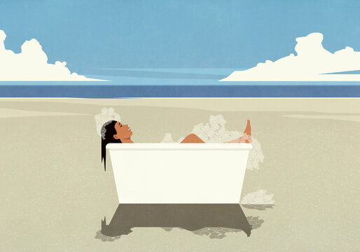 Carefree woman enjoying bubble bath in bathtub on sunny ocean beach
