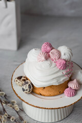 Beautiful stylish still life. Easter cake with meringue, marshmallows, Easter eggs and willow twigs on a light concrete background. happy Easter 2024.