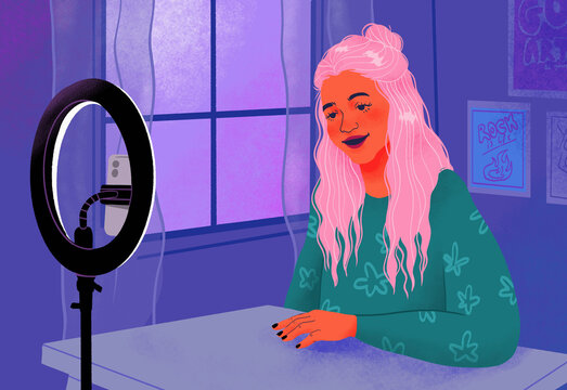 Smiling female influencer filming behind ring light and smart phone at window

