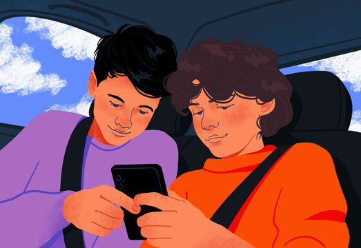 Tween brothers using smart phone together in back seat of car
