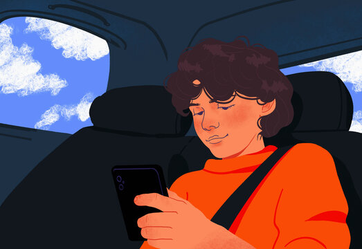 Boy with smart phone riding in back seat of car
