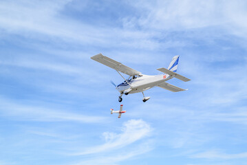 Single engine ultralight plane flying in the blue sky with white clouds