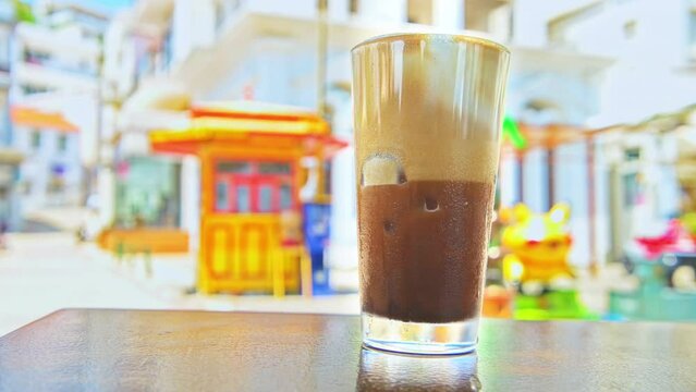 Freddo cappuccino espresso coffee drink beverage in glass cup on table at sidewalk street cafe restaurant of Ikaria Greek island, Greece