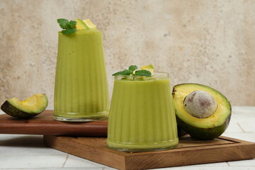 Fresh avocado smoothie with whole and slices avocado fruit on white background