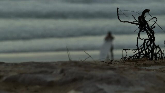 Blurred surfer on the beach with some sticks in the foreground.