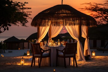 A couple enjoys a candlelit dinner on a serene indian beach, savoring a sumptuous seafood spread as the sun sets over the ocean.