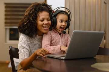 Happiness mother and daughter use laptop and headphone for entertain , family joyful together in...