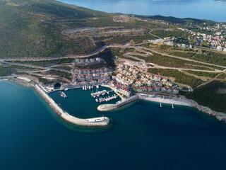 Aerial view of Lustica Bay, Adriatic sea, Montenegro. Top view of buildings, Harbor Marina with moored boats and yachts and lighthouse against the backdrop of mountains. New modern luxury resort - obrazy, fototapety, plakaty