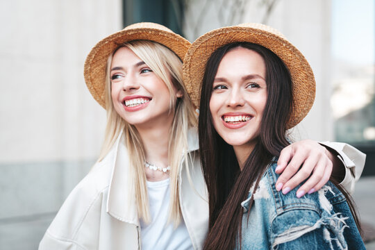 Two young beautiful smiling hipster female in trendy summer clothes. Carefree women posing in the street. Positive models having fun outdoors at sunny day. Cheerful and happy. In hat