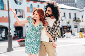 Naklejka premium Smiling beautiful redhead woman and her handsome boyfriend. Model in casual summer clothes. Happy cheerful family. Female having fun. Couple posing in the street at sunny day