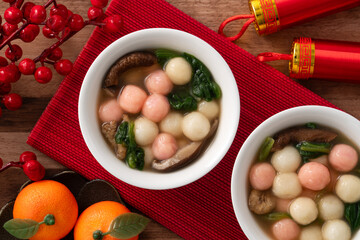 Eating red and white small tangyuan with savory soup and vegetable for lunar new year festival.