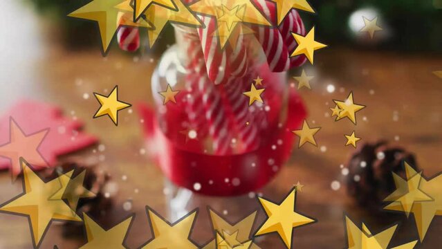 Animation of yellow stars over jar with candy canes and pinecones on wood surface
