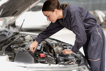 Auto mechanic in uniform service car engine in workshop garage. Skill female repairman using tool repair maintenance vehicle automobile. Young adult technician working examining in transportation shop