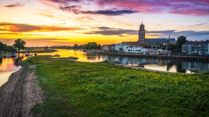 Scenic view of the town of Deventer along a river in the Netherlands at sunset - obrazy, fototapety, plakaty