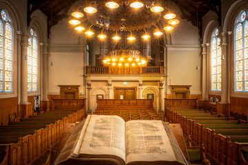 Open Bible book placed in the center of a wooden pew-filled church