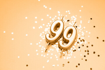 99 years celebration festive background made with golden candles in the form of number Ninety-nine lying on sparkles. Universal holiday banner with copy space.