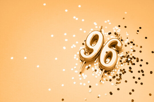 96 years celebration festive background made with golden candles in the form of number Ninety-six lying on sparkles. Universal holiday banner with copy space.