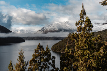 Scenic view of a lake surrounded by snowy mountains and green forests