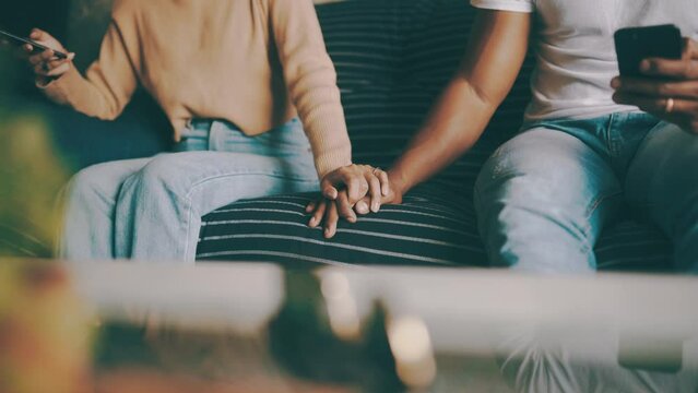 Couple, holding hands and phone or connection for bonding, couch and technology for communication. Mobile application, internet and commitment in marriage, people and together at home on website