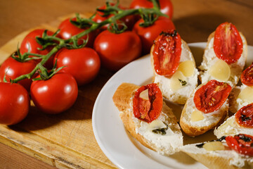 sandwiches with red sun-dried tomatoes and cheese on a plate on the table next to fresh tomatoes