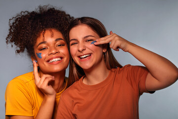 Female friendship. Two happy multi-ethnic teen girls friends having fun while applying face mask