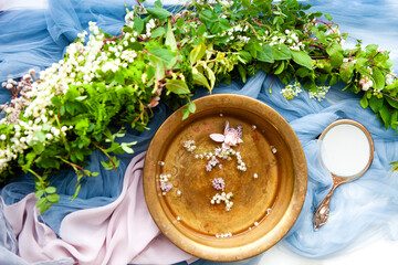 Fancy hand mirror and bowl of water among leaves and flowers prepared for skin care procedure - obrazy, fototapety, plakaty