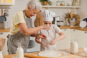 Happy family in kitchen. Grandmother and granddaughter child cook in kitchen together. Grandma...