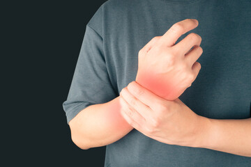 Man suffering from wrist hand pain over black background. Causes of hurt include carpal tunnel...