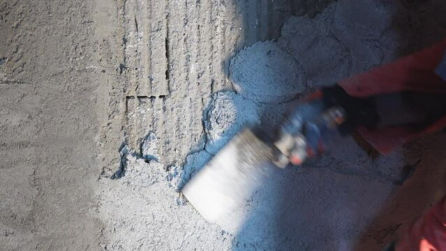 Workman plastering with cement mortar the building wall interior