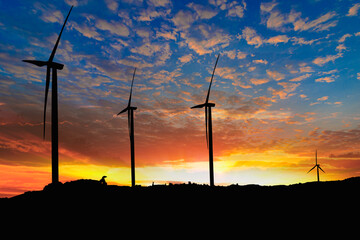 Obraz premium Silhouette of a wind turbine generating electricity on sky sunset background ,from wind power for environmental,clean energy concept
